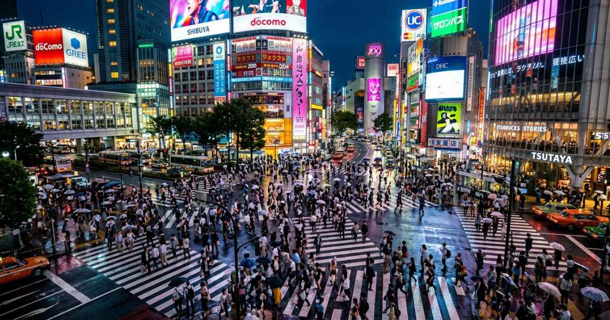 Pedestrians crossing the famous Shibuya Scramble Crossing in Tokyo, Japan at dusk.