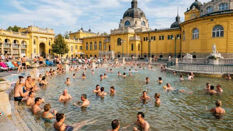 Visitors relaxing in the outdoor thermal water pools at Széchenyi Baths in Budapest.