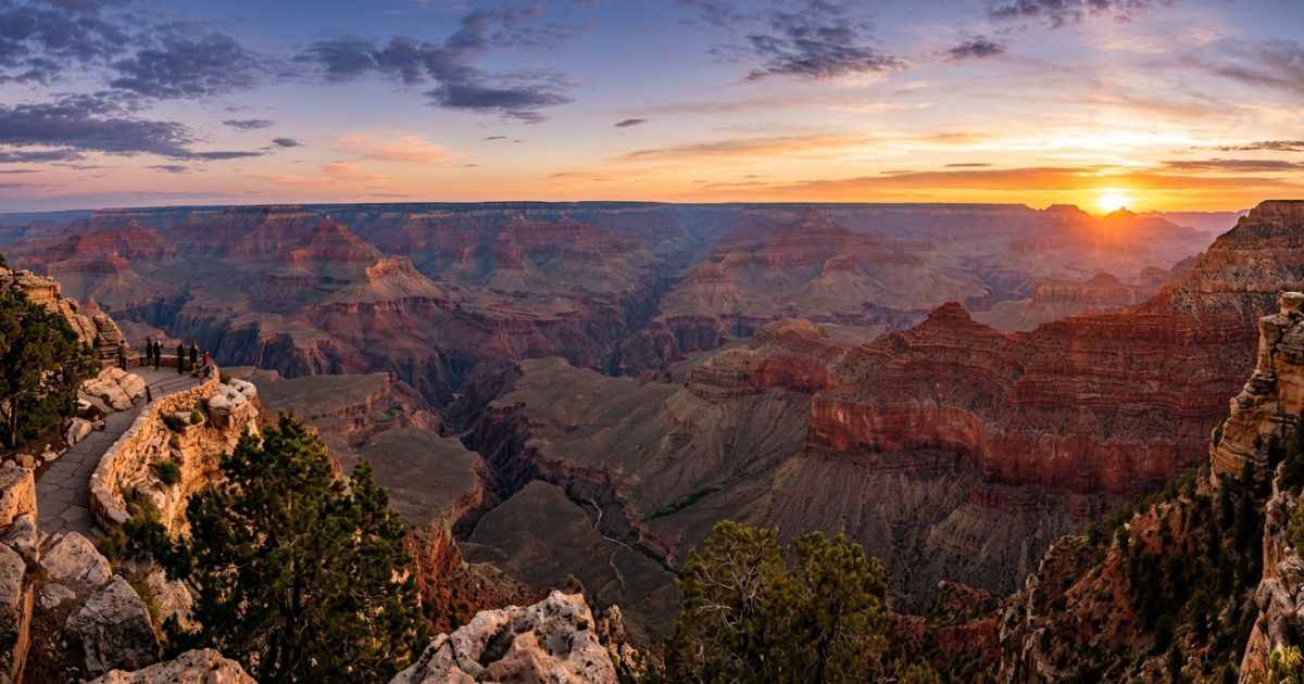 Panoramic view of the Grand Canyon at sunset with vibrant orange and red rock layers.