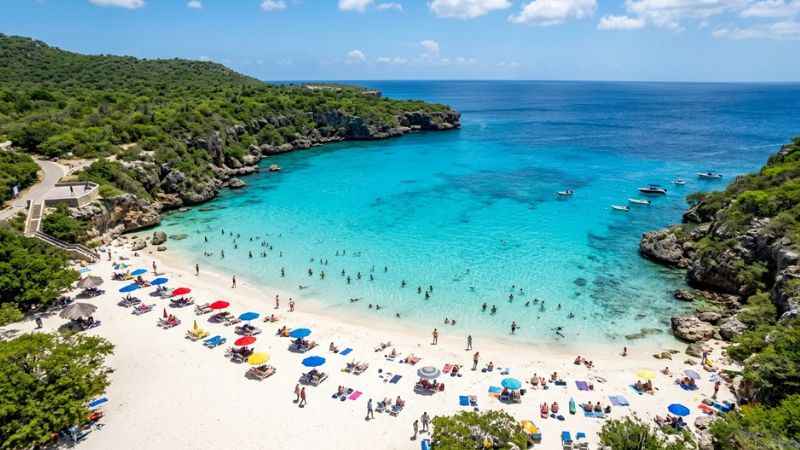 Visitors enjoying the scenic beach and blue water at Grote Knip in Curaçao.