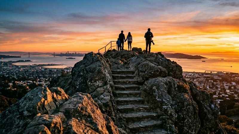 Visitors standing on top of Indian Rock Park watching the sunset over the East Bay.