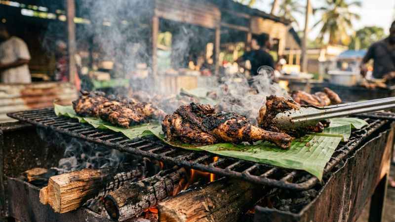 Authentic Jamaican jerk chicken grilling over wood smoke at a popular Montego Bay spot.