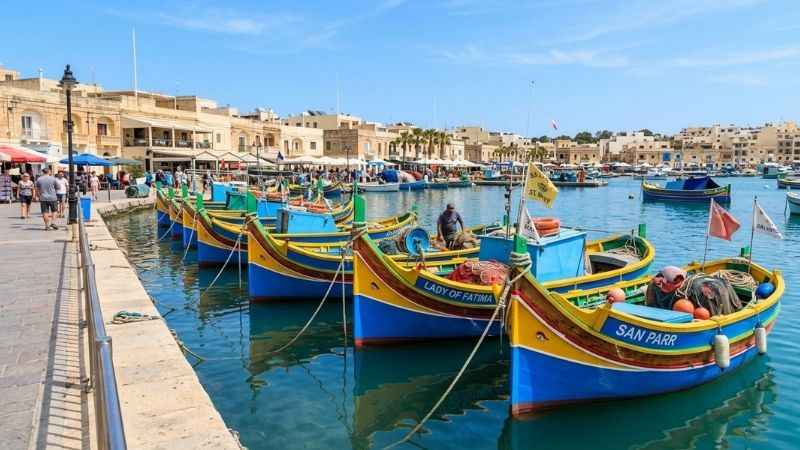 Traditional painted luzzu fishing boats docked in Marsaxlokk harbor Malta