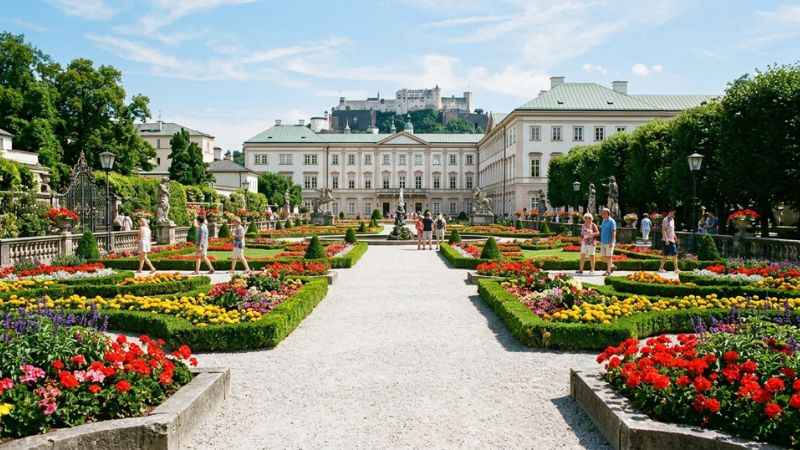 Visitors walking through the manicured floral pathways of Mirabell Gardens in Salzburg.