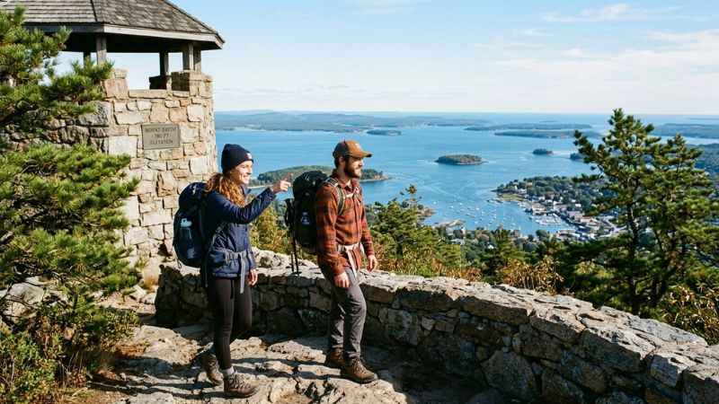 Hikers enjoying the panoramic ocean view from the top of Mount Battie in Camden Maine.