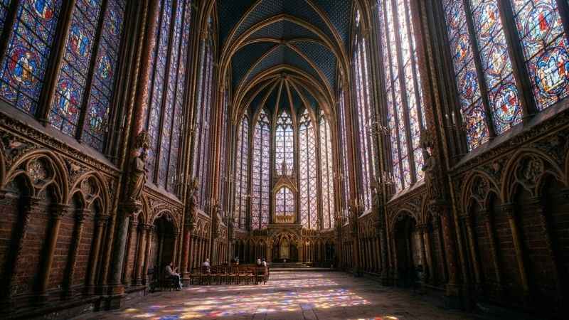 Sunlight streaming through the towering Gothic stained-glass windows of Sainte-Chapelle in Paris.