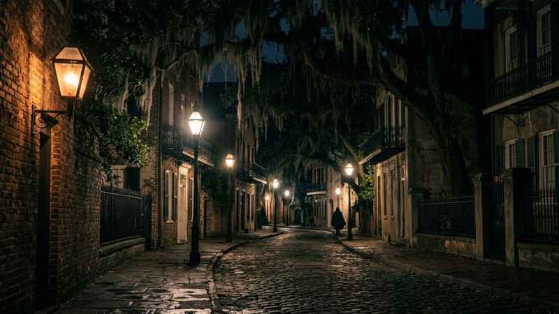 Atmospheric night shot of a historic Savannah street with gas lamps.