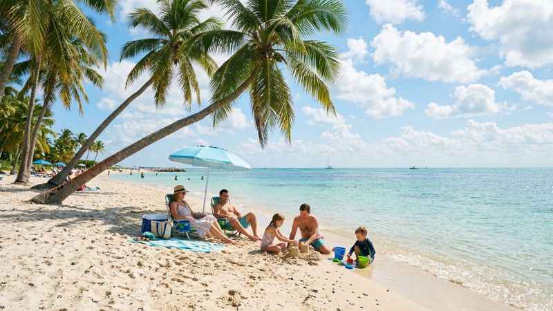 Families enjoying the sandy shore and water at Sombrero Beach in Marathon, Florida.