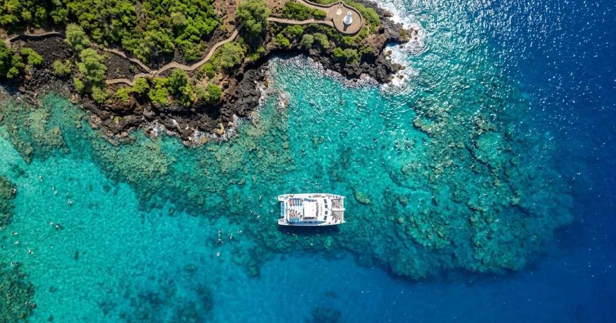 Aerial view of clear blue water and snorkel boats at Kealakekua Bay in Kona, Hawaii.