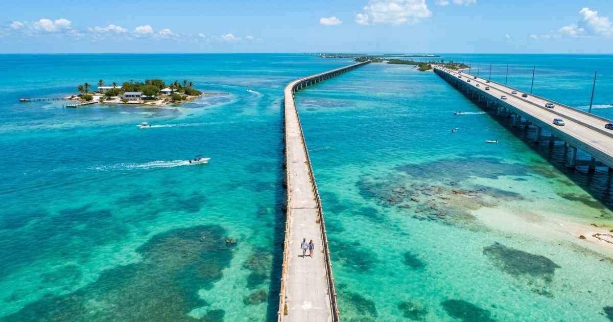 People walking along the historic Old Seven Mile Bridge in Marathon, Florida over clear blue water.
