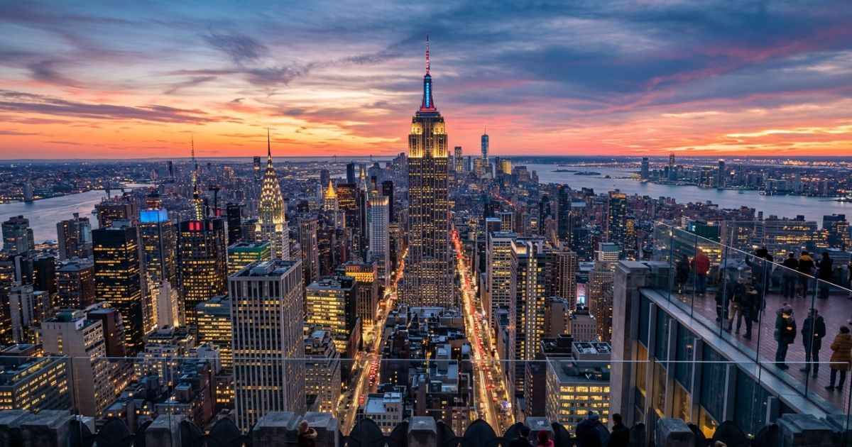 Aerial skyline view of Manhattan buildings and the Empire State Building at sunset in New York City.
