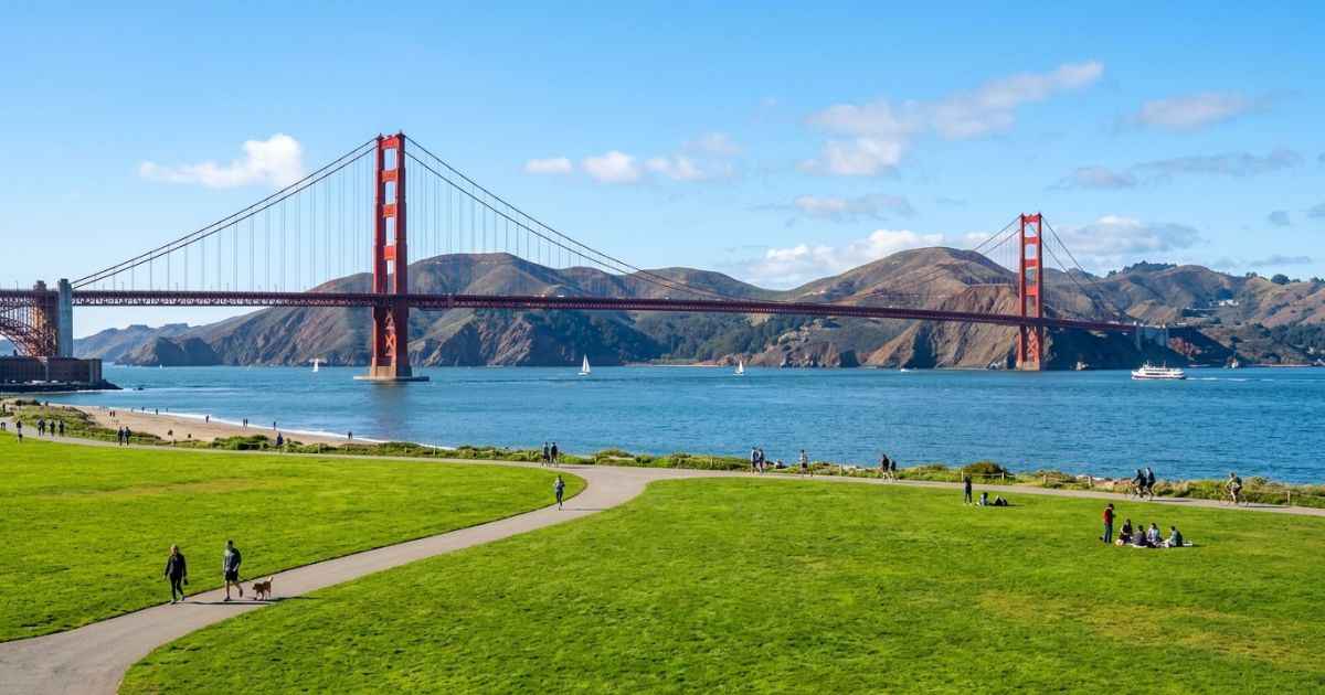 View of the Golden Gate Bridge framed by green lawns and blue bay water at Crissy Field in San Francisco.