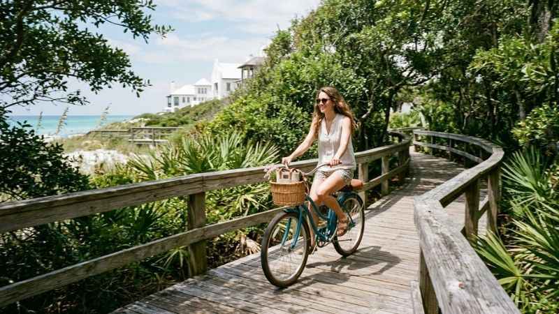 Visitor riding a bicycle along a scenic wooden boardwalk path in Rosemary Beach