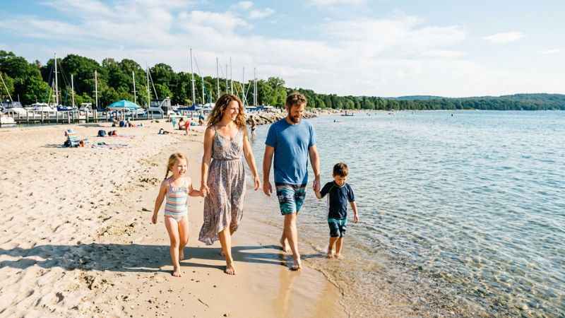 Families enjoying the sandy beach and calm water at Clinch Park Beach in Traverse City.