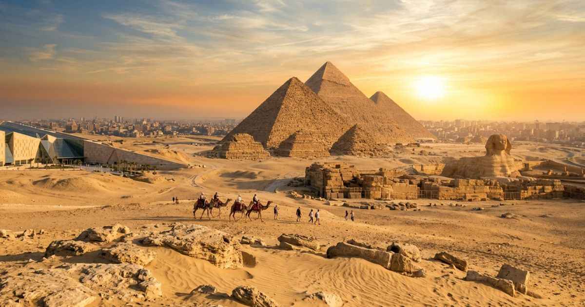 Cinematic wide-angle view of the Giza Pyramids glowing under a golden desert sunrise, with the sleek modern architecture of the Grand Egyptian Museum visible in the foreground.