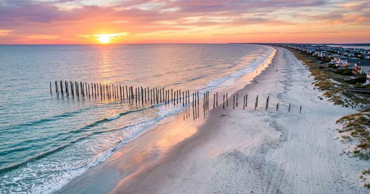 Aerial view of the Holden Beach shoreline and uncrowded white sand beach at sunset.
