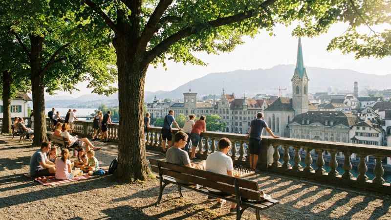 Tourists and locals relaxing at Lindenhof hill viewpoint overlooking Zurich rooftops.