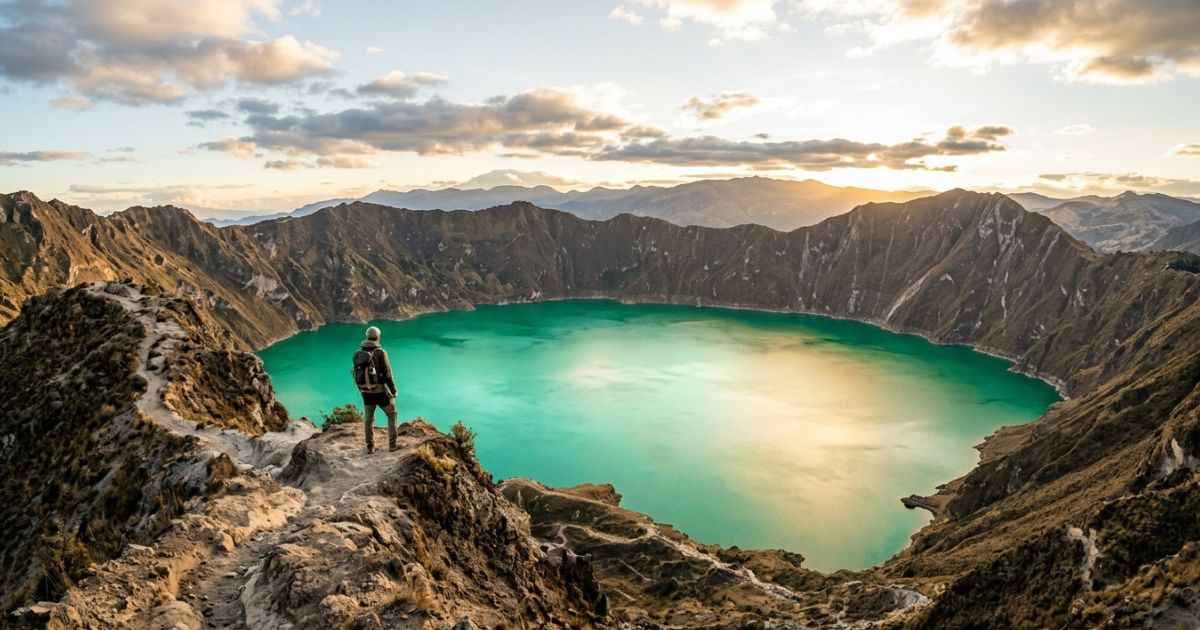 Hiker looking at the turquoise water of Quilotoa crater lake in the Ecuadorian Andes.