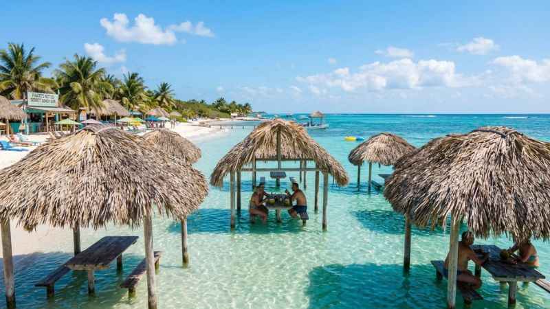 Clear turquoise water and beach palapas at Secret Beach in San Pedro Belize.
