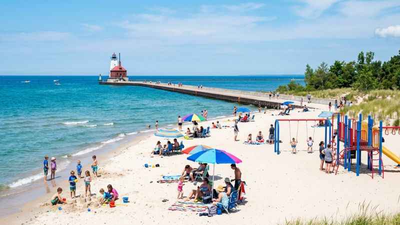 Visitors walking along the concrete pier toward the Ludington North Breakwater Light next to Stearns Park Beach on Lake Michigan.
