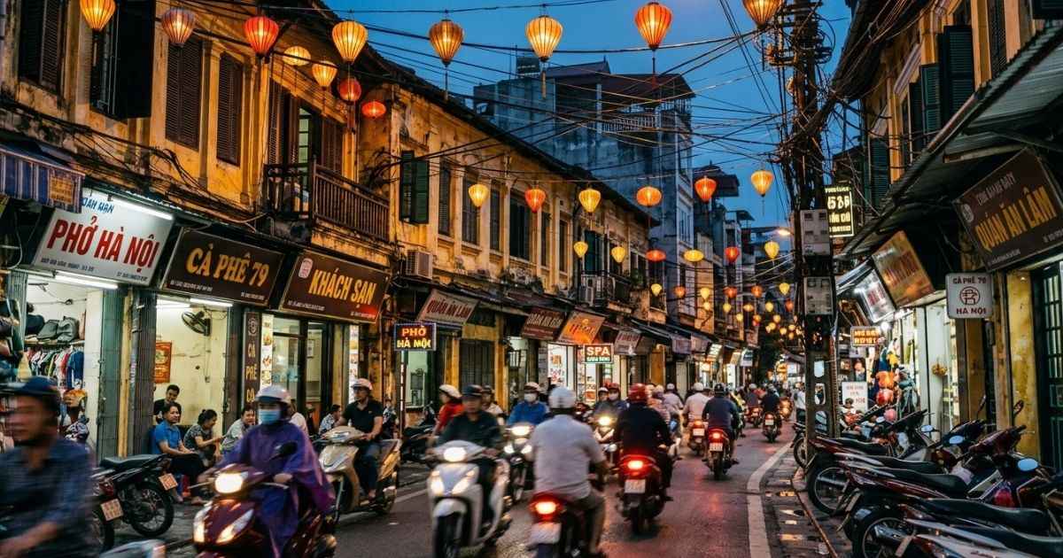 Vibrant street scene in the Hanoi Old Quarter with glowing lanterns and motorbikes at dusk.