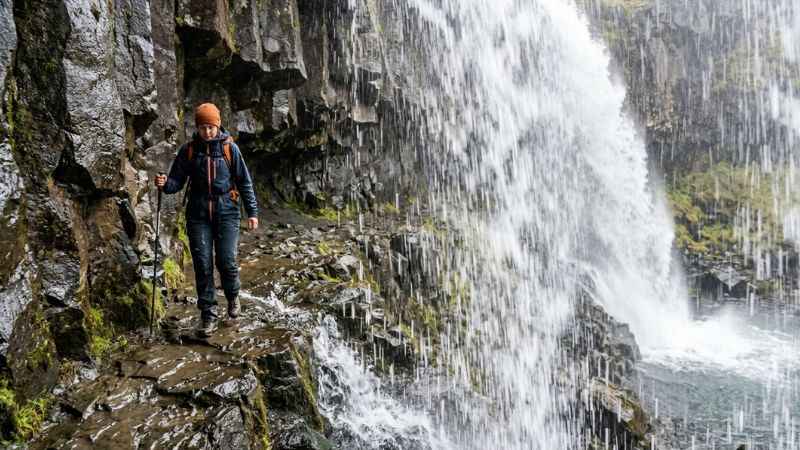 Person walking behind the cascading water of Perrine Coulee Falls in Twin Falls.