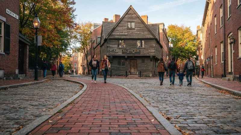 Tourists walking along the red brick line of the Freedom Trail past the historic Paul Revere House in Boston.