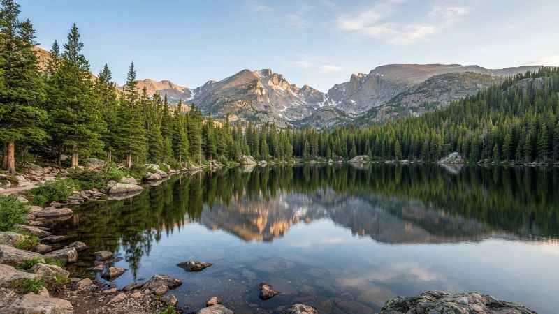 Clear water of Bear Lake surrounded by pine trees and rocky mountain peaks.