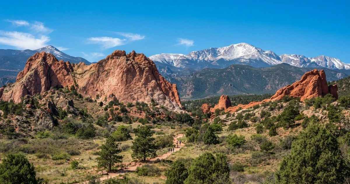 Red rock formations framed against snowy mountain peaks under a clear blue sky in Colorado.